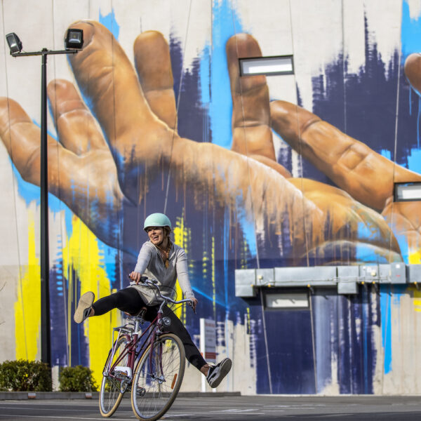Girl on a bike with graffiti behind them. Christchurch Street Art - Have You Ever - Miles Holden. new zealand south island itinerary