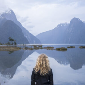 girl standing looking at Milford Sound. Milford Sound, Fiordland, New Zealand, By Will Patino