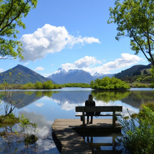 Lady sitting on a bench, Glenorchy is nestled on the northern shores of Lake Wakatipu, New Zealand