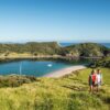 Couple walking with the islands in the background. Bay of Islands on our Small Group New Zealand Tours